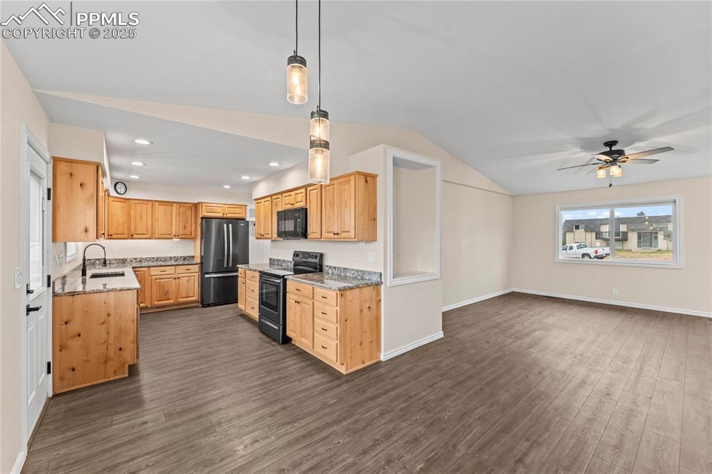 Image 7 of 34: Kitchen with electric range oven, black microwave, freestanding refrigerato