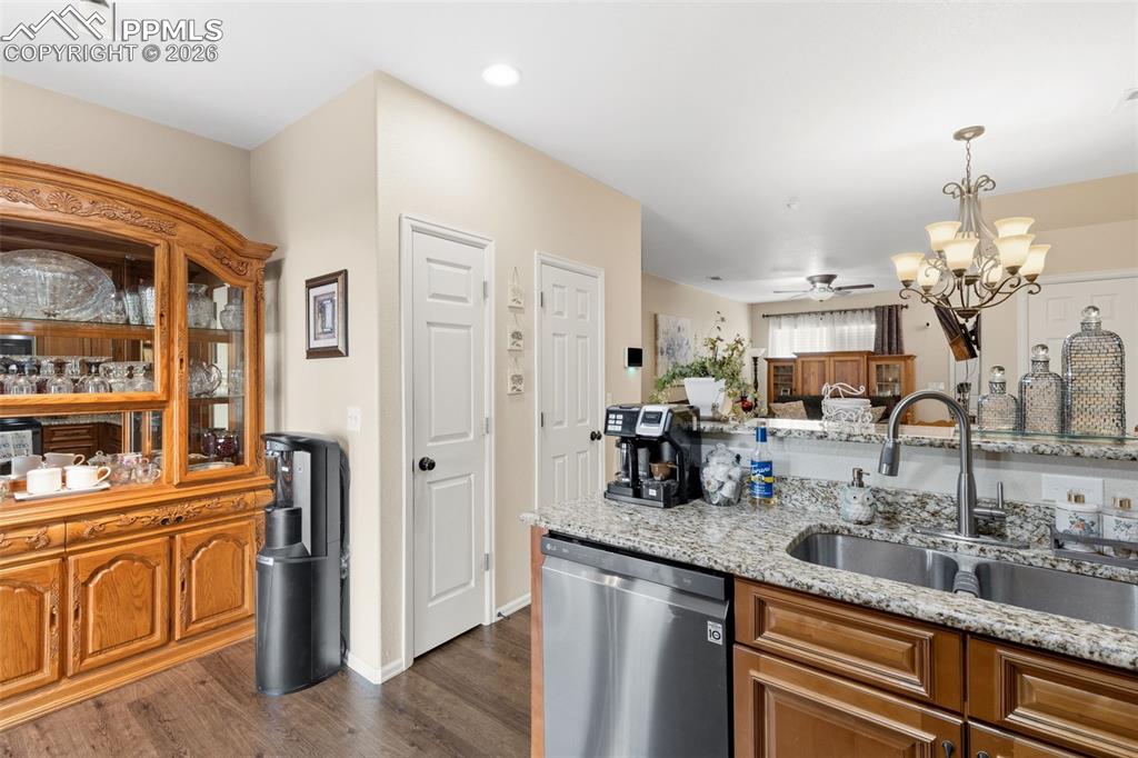 Image 11 of 26: Kitchen featuring a chandelier, light stone countertops, dishwasher, wood f