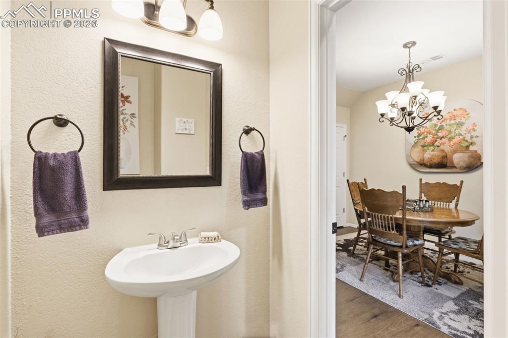 Image 12 of 26: Bathroom featuring hanging lights, wood finished floors, and a textured wal