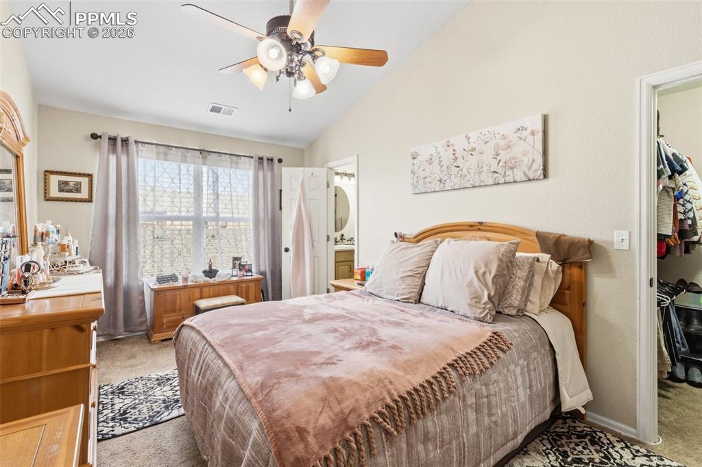 Image 16 of 26: Bedroom featuring light colored carpet, a walk in closet, lofted ceiling, a