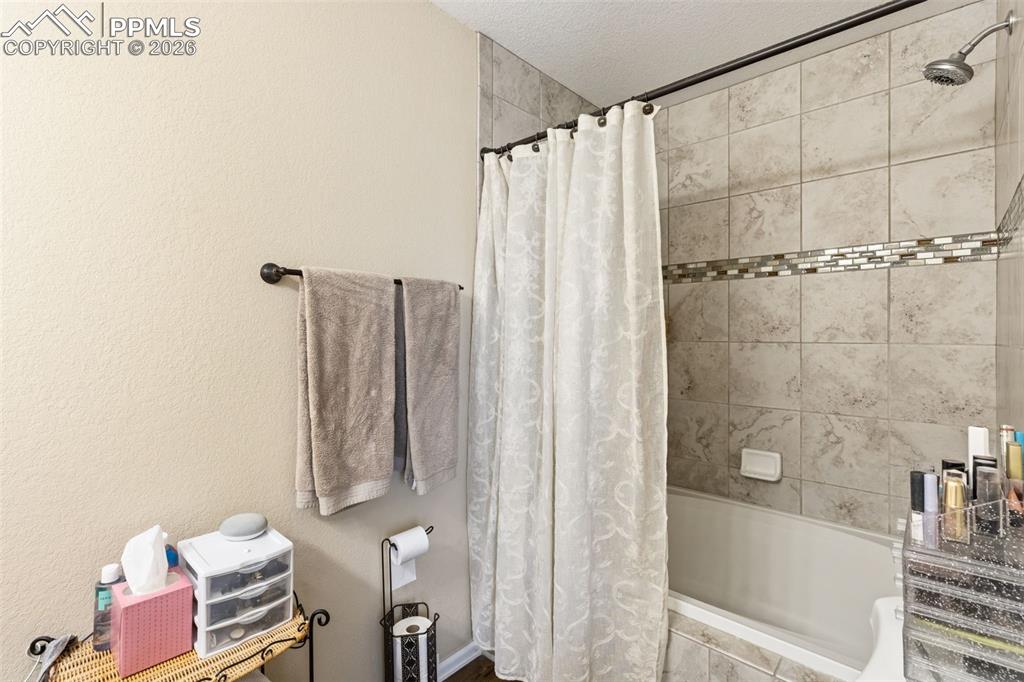 Image 20 of 26: Full bath featuring tiled shower / bath combo and a textured ceiling