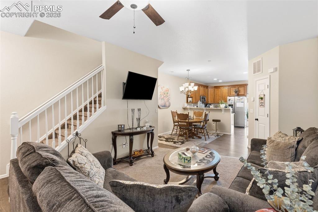 Image 4 of 26: Living area with a ceiling fan, light wood finished floors, and hanging lig