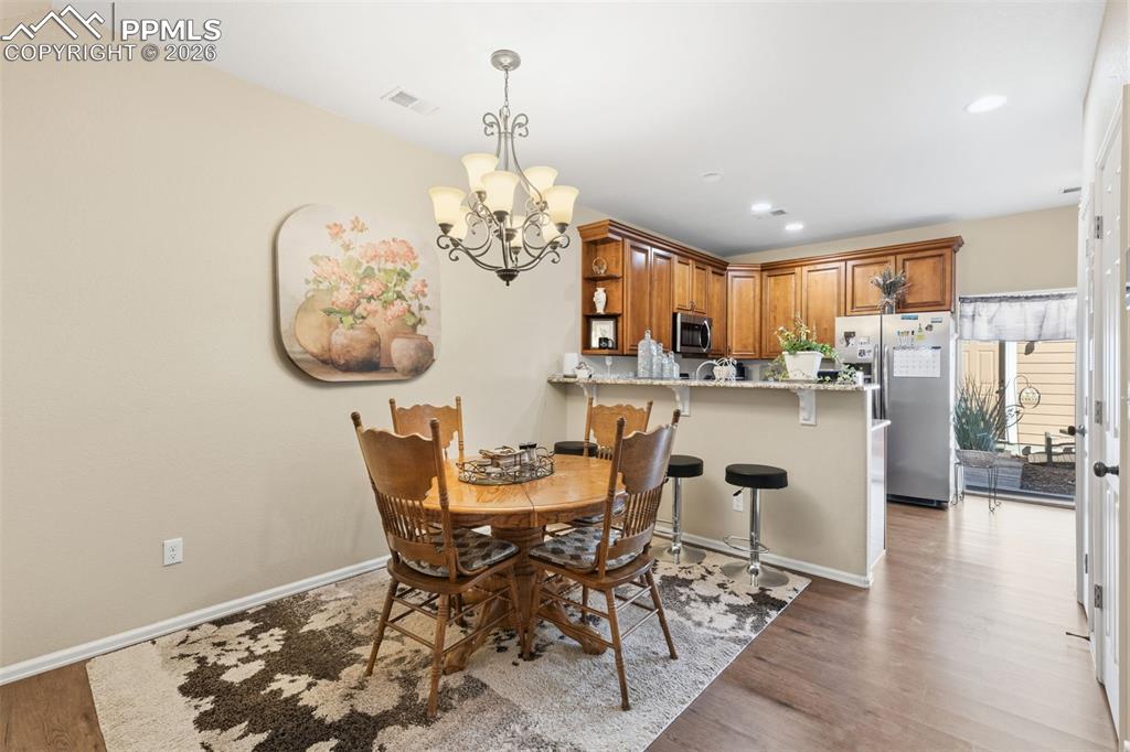Image 6 of 26: Dining space with dark wood-style flooring and hanging lights