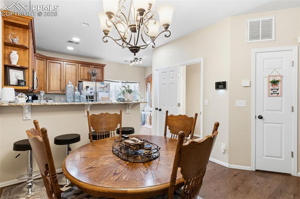 Image 8 of 26: Dining room with hanging lights and dark wood-style flooring