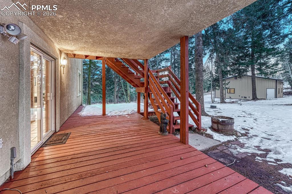 Image 2 of 40: large covered deck and attached uncovered deck and steps to front door on m