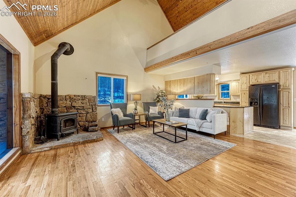 Image 5 of 40: Living room with vaulted ceilings, woodstove with moss rock surround and lo