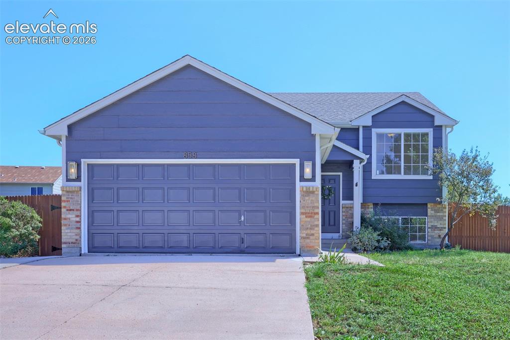 Image 1 of 35: Split-level residence featuring a two-car garage with a paneled door, brick