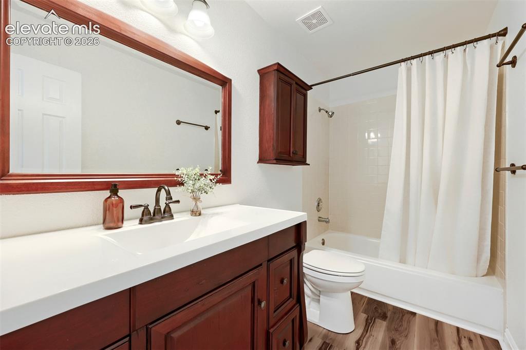 Image 17 of 35: Wood-finish flooring, single vanity with a white countertop, large framed m