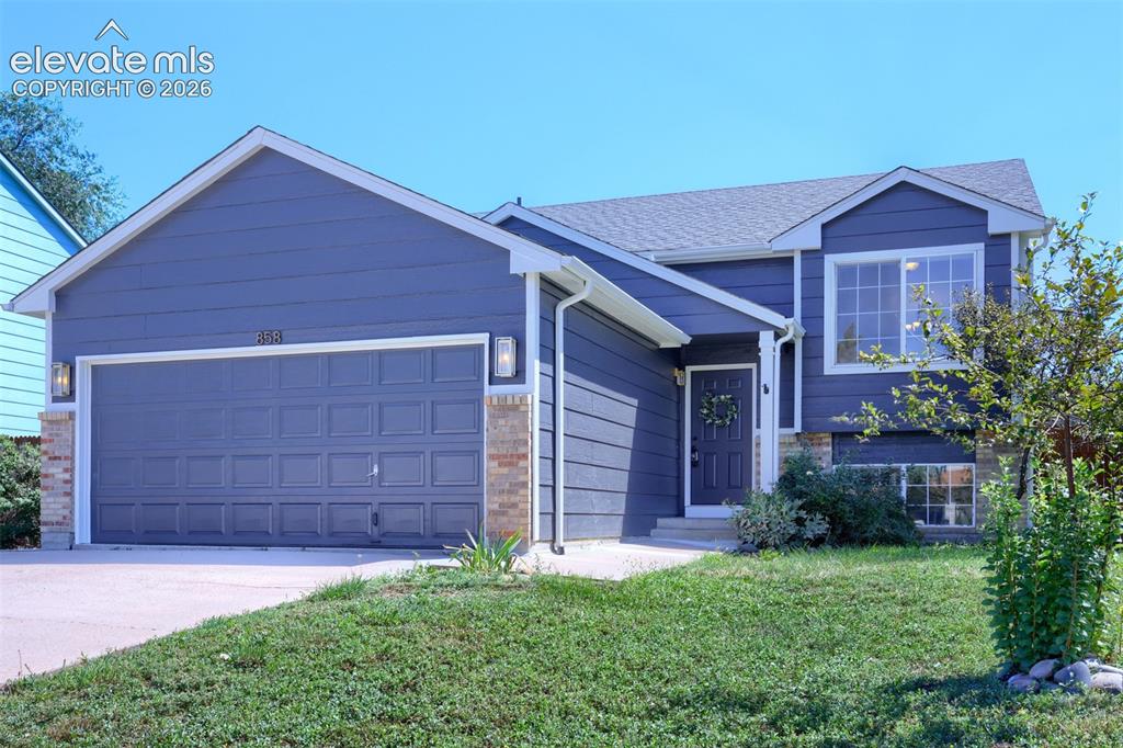 Image 2 of 35: Gable roofline, architectural shingles, paneled garage door, brick facade a