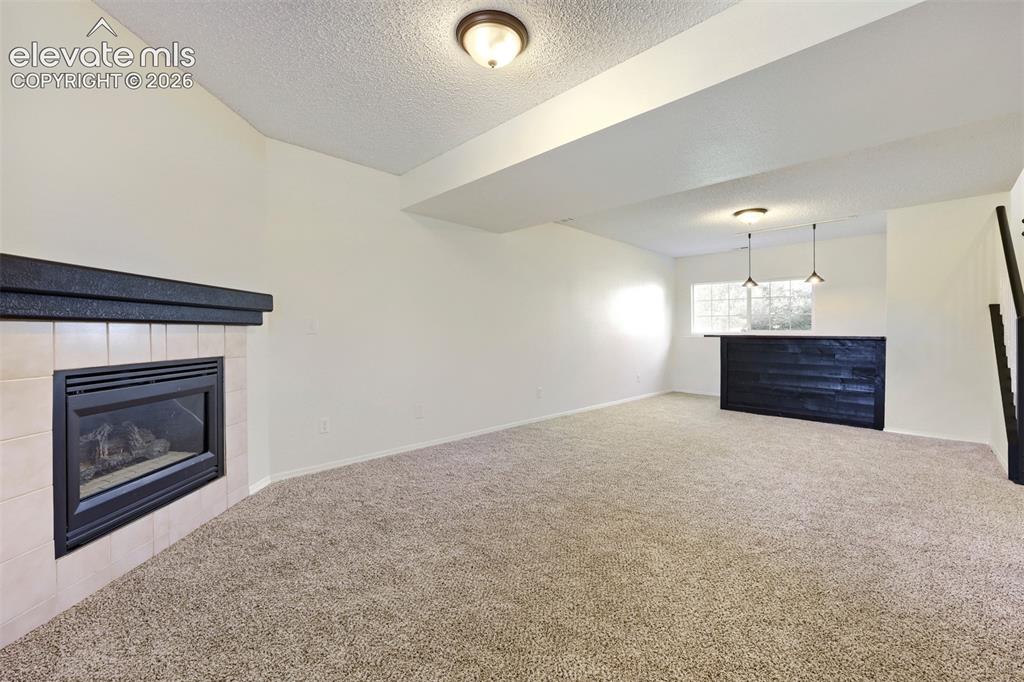Image 21 of 35: Spacious room featuring carpeting, a built-in fireplace with a tiled surrou
