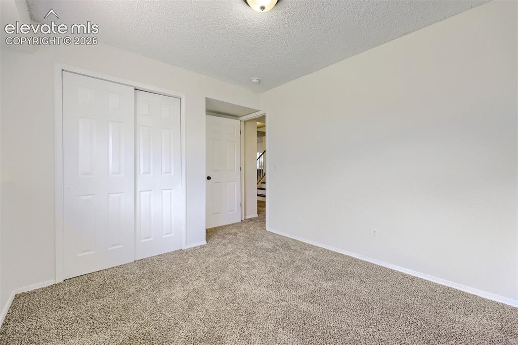 Image 24 of 35: Carpeted flooring, white walls, built-in closet with sliding panel doors, a