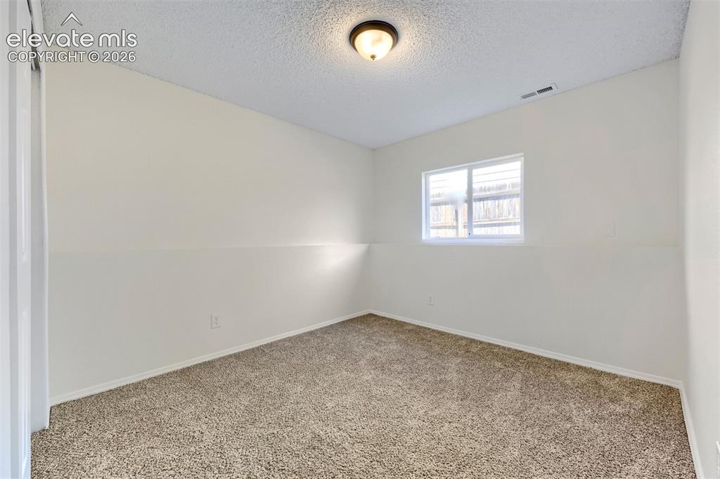 Image 25 of 35: Neutral wall tones with a textured ceiling, carpeted flooring, and a single