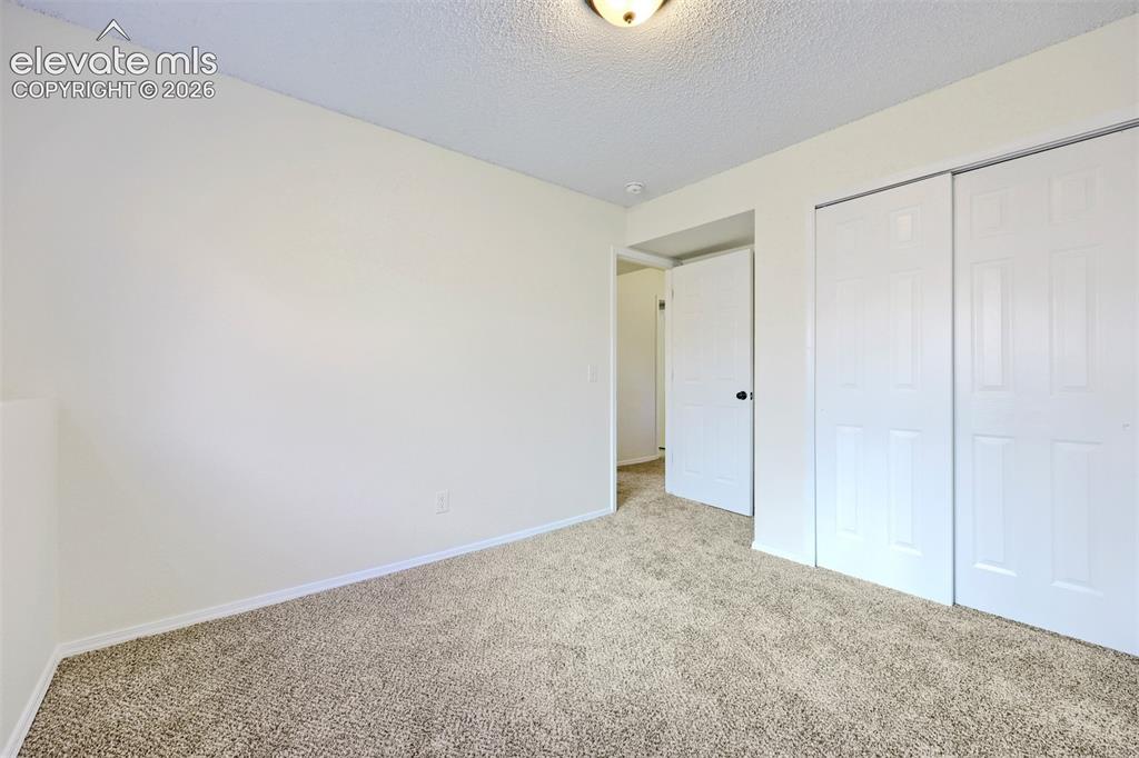 Image 26 of 35: Neutral wall paint, textured ceiling, wall-to-wall carpeting, paneled inter