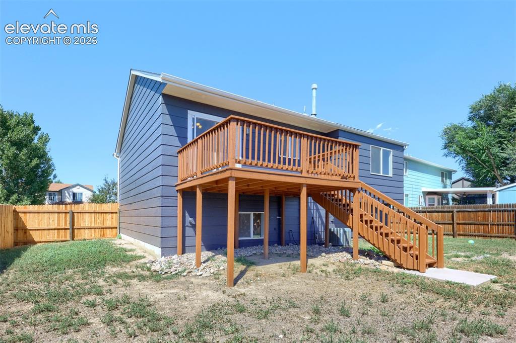 Image 28 of 35: Rear exterior featuring a wood deck, wood staircase, horizontal siding, and