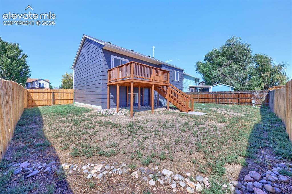 Image 29 of 35: Expansive backyard with a wood privacy fence, multi-level wood deck, and wa