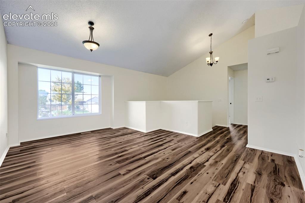 Image 3 of 35: Vaulted ceiling with a contemporary chandelier, large picture window, wood-