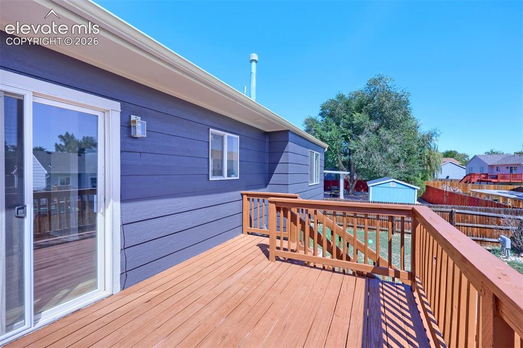 Image 32 of 35: Expansive wood deck with wood railings, sliding glass door access, and exte
