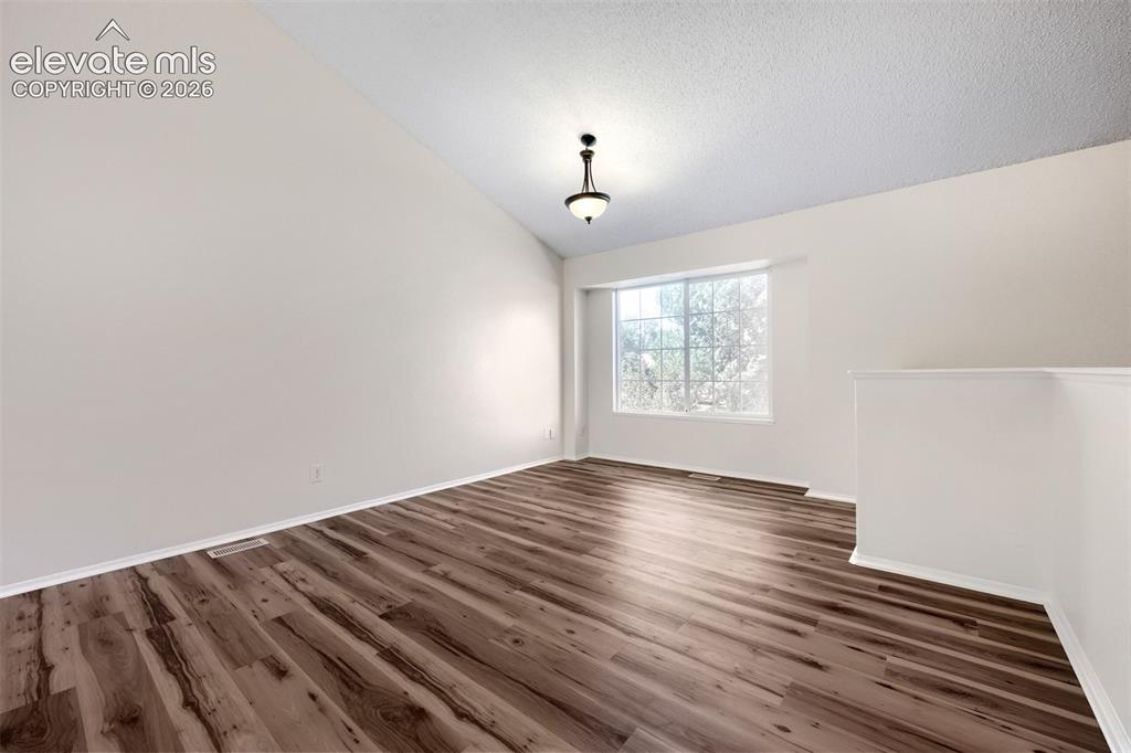 Image 4 of 35: Spacious room featuring vaulted ceilings, wood-finish flooring, a contempor