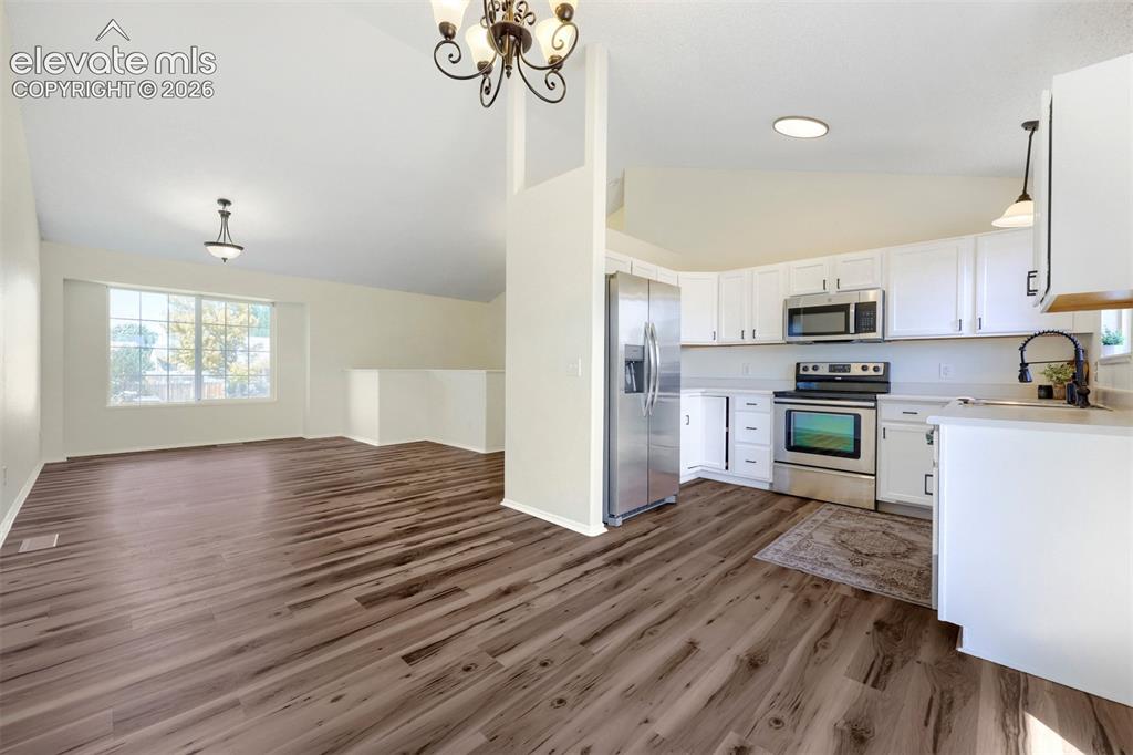 Image 7 of 35: Vaulted ceilings, wood-finish flooring, white cabinetry, stainless steel ap