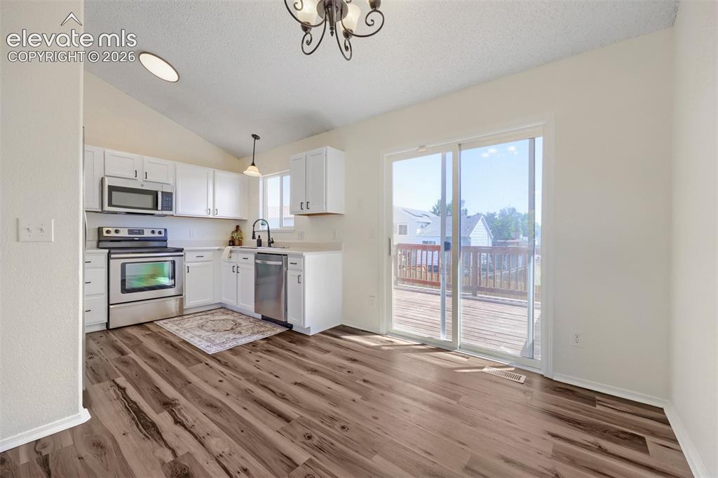 Image 8 of 35: Kitchen featuring white cabinetry, stainless steel appliances, wood-finish