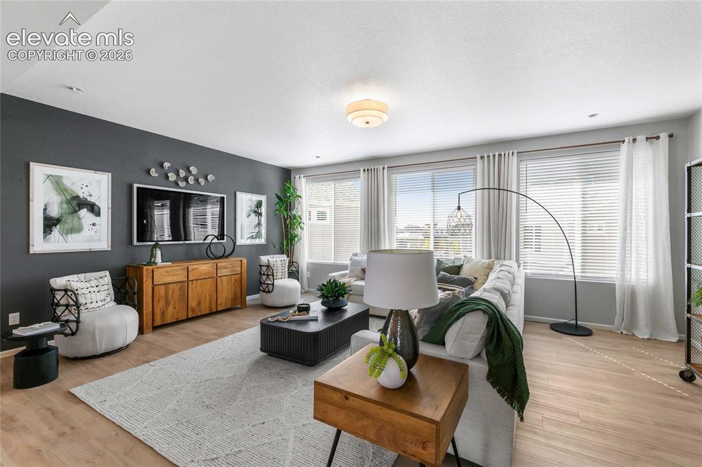 Image 19 of 31: Expansive living area with wood-finish flooring, a wall of windows, and a b