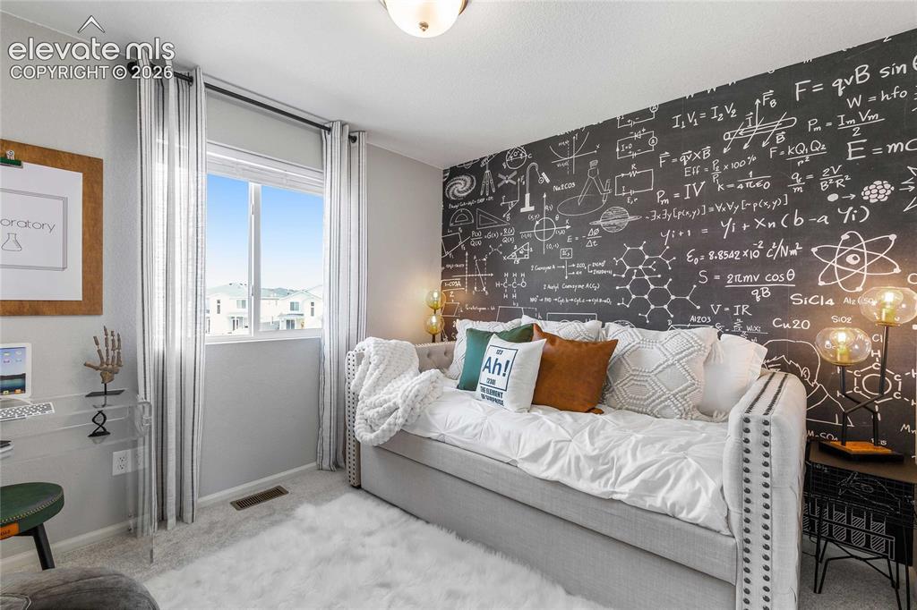 Image 28 of 31: Spacious room featuring a large window with vertical blinds, textured carpe
