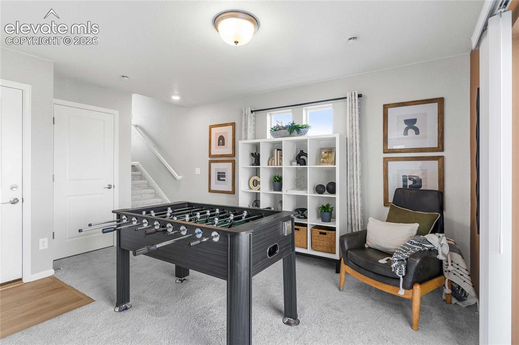 Image 9 of 31: Recreation room featuring a foosball table, built-in shelving with decorati