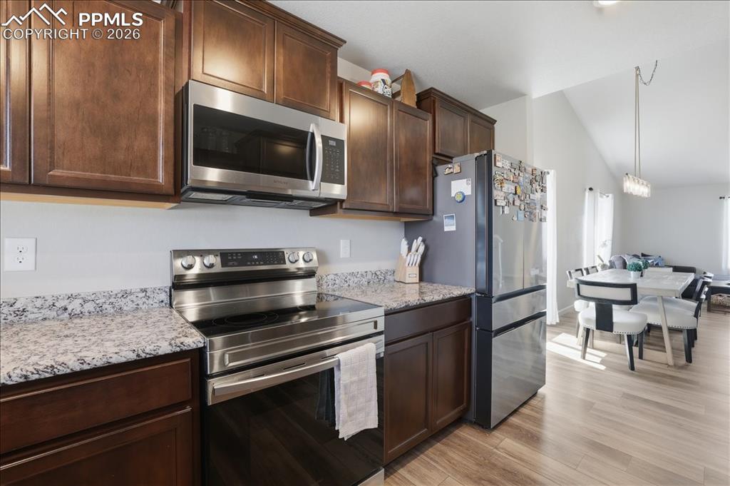 Image 10 of 47: The kitchen features wood cabinetry, stainless steel appliances, and granit