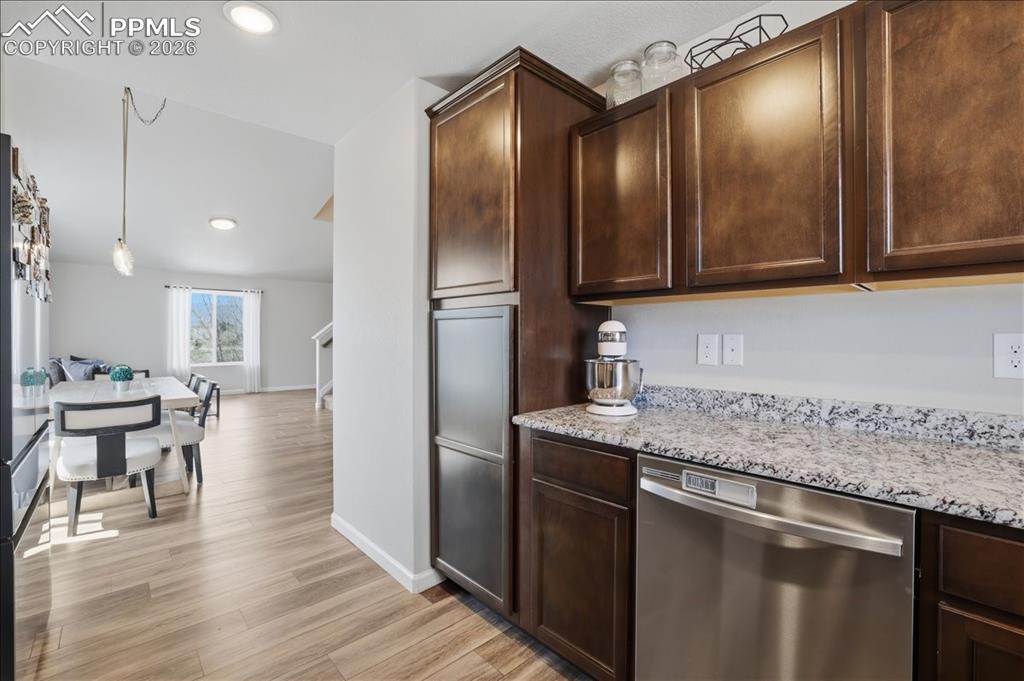 Image 11 of 47: The kitchen features dark wood cabinetry, a light-colored granite counterto