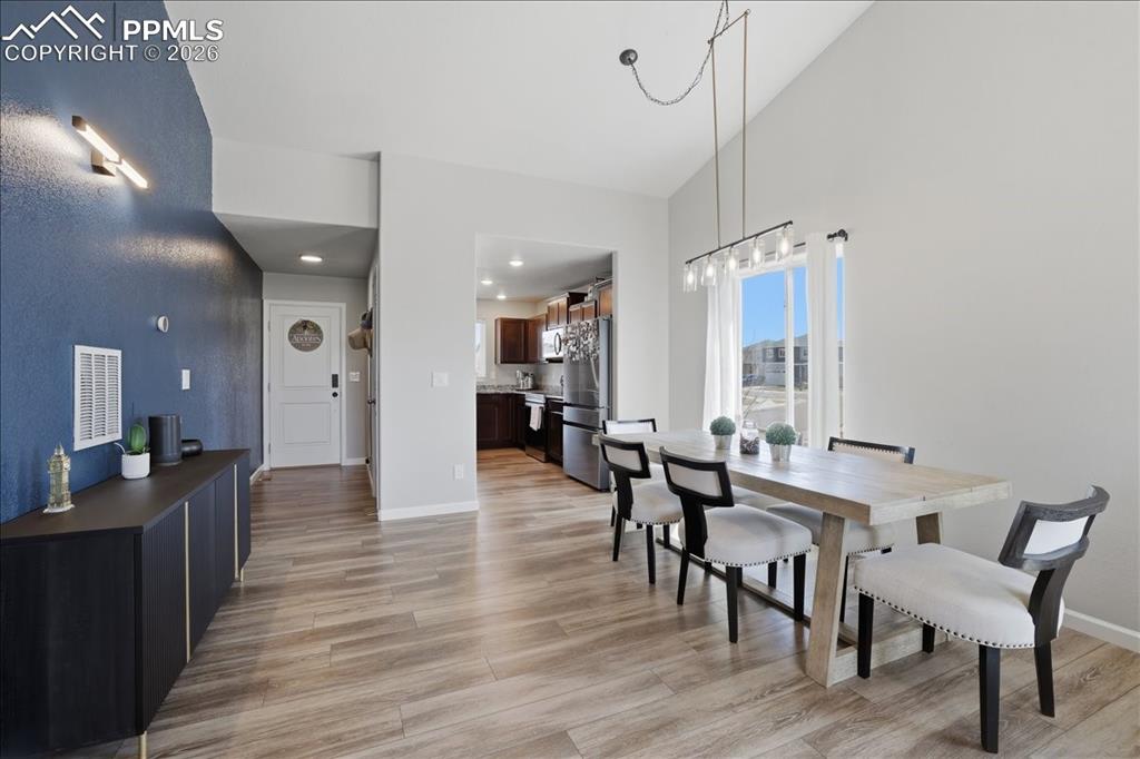 Image 12 of 47: The dining area showcases high ceilings, a window with curtains, and a mode