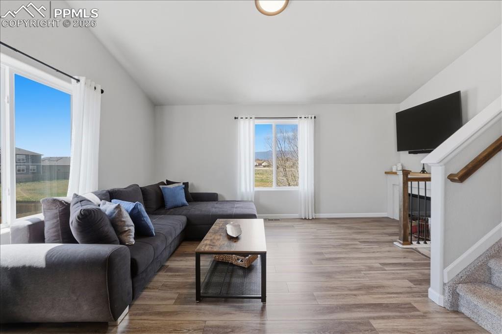 Image 14 of 47: The living area features vaulted ceilings, large windows, and hardwood styl