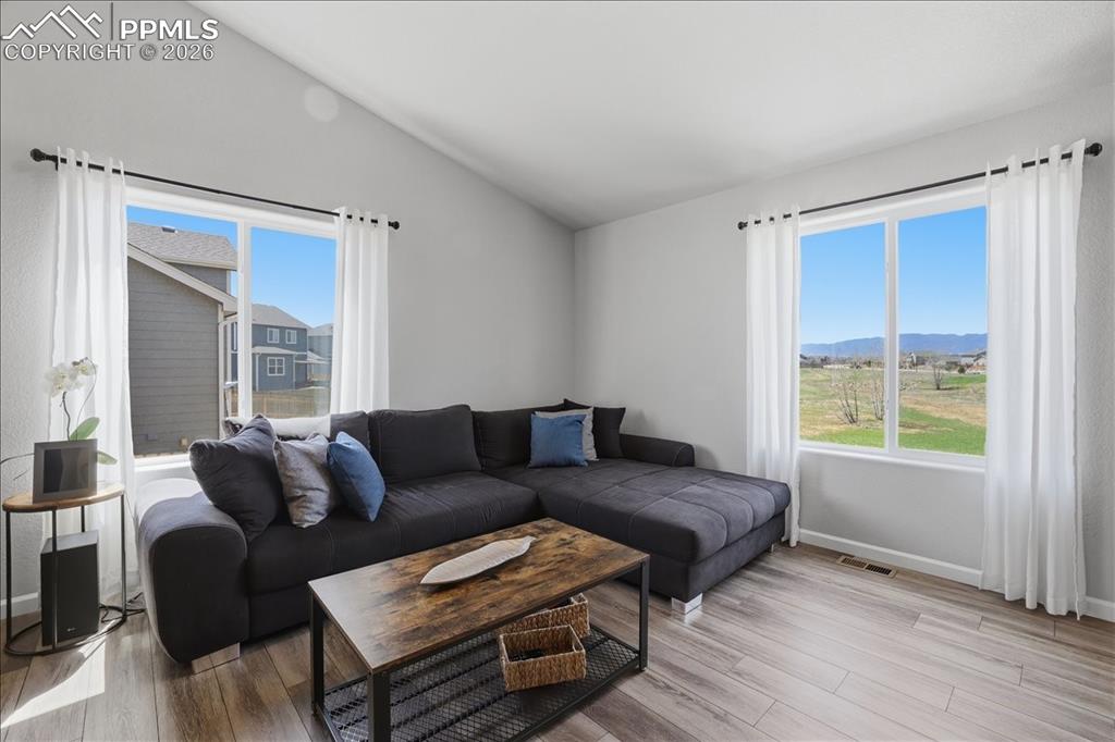Image 15 of 47: Living area featuring vaulted ceilings, large windows with white curtains, 