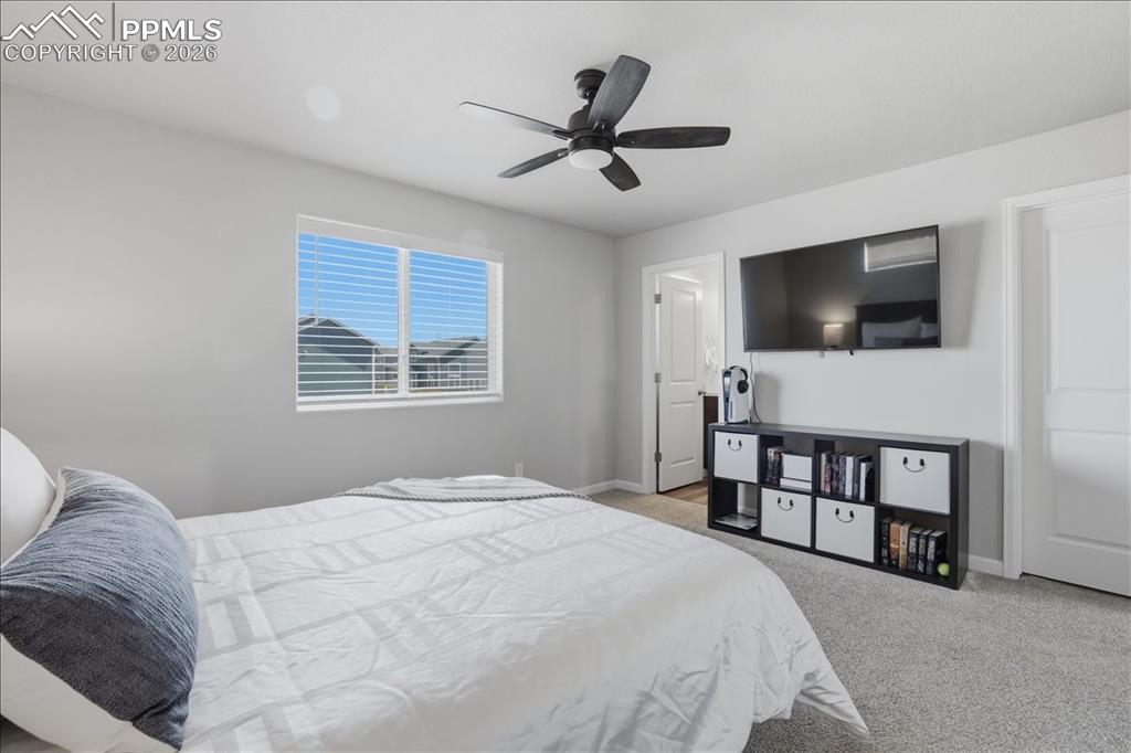 Image 21 of 47: The room features light gray walls, a window with blinds, and a ceiling fan
