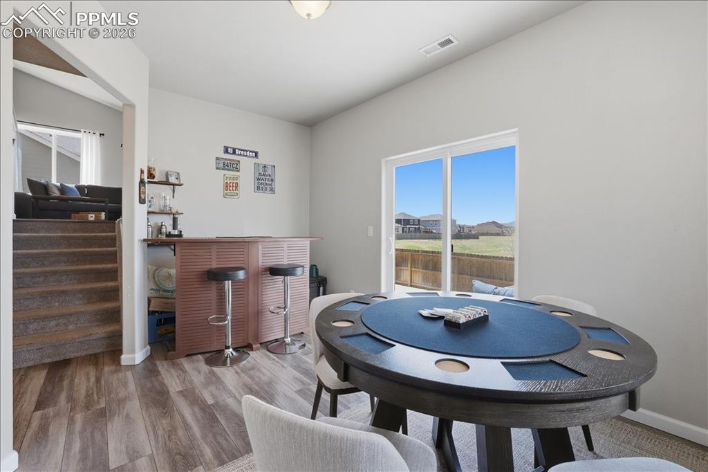 Image 28 of 47: Recreation area with wood-look flooring, a sliding glass door, and a bar ar