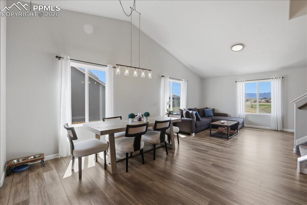 Image 3 of 47: The property features an open living and dining area with vaulted ceilings,