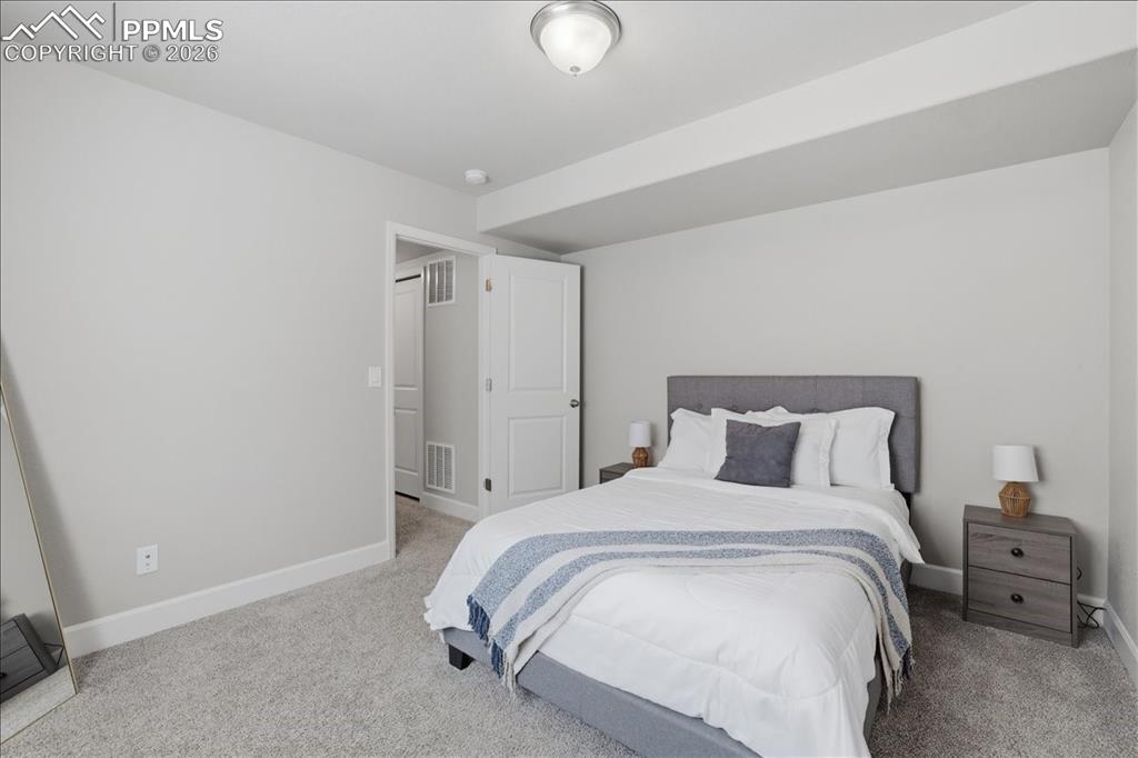 Image 34 of 47: The room features light gray walls and plush gray carpeting