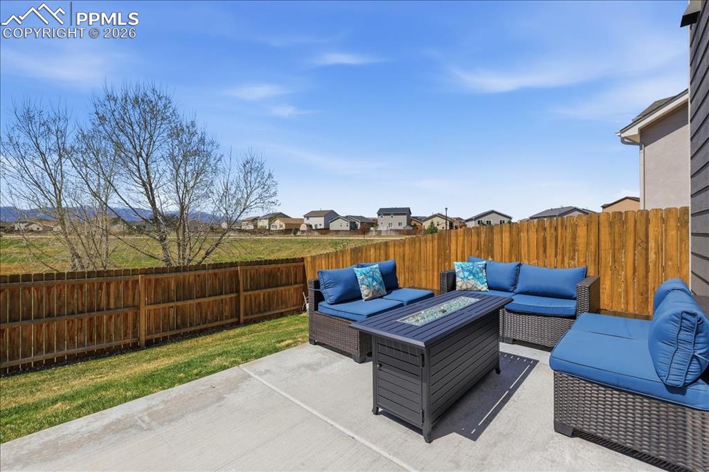 Image 38 of 47: This property features a concrete patio area, a wooden fence, and a grassy 