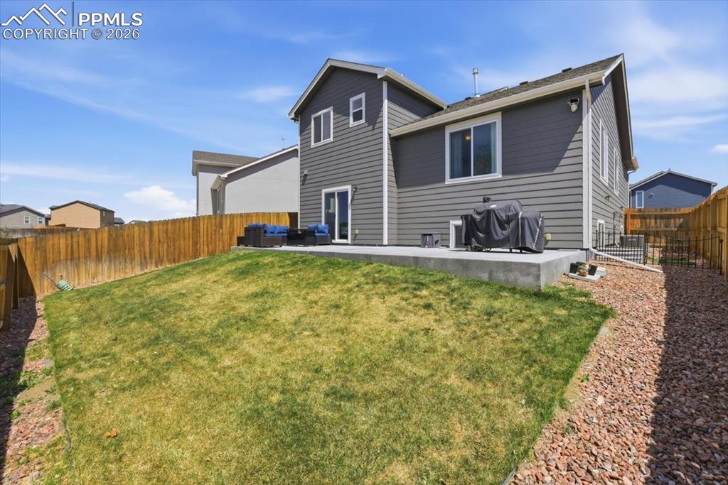 Image 40 of 47: The property features a private backyard with a lawn, a wooden fence, and a