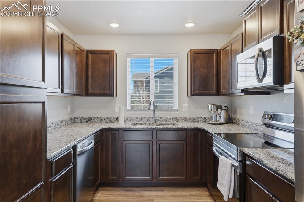 Image 8 of 47: The kitchen features dark wood cabinetry, granite countertops, and stainles