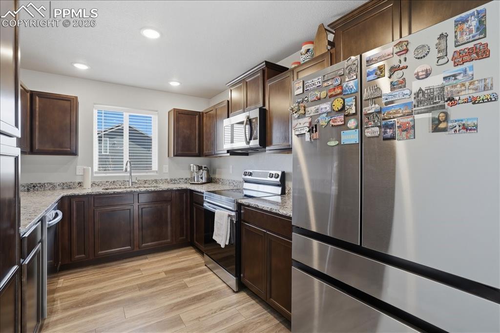 Image 9 of 47: The kitchen features dark wood cabinetry, light-colored countertops, and st
