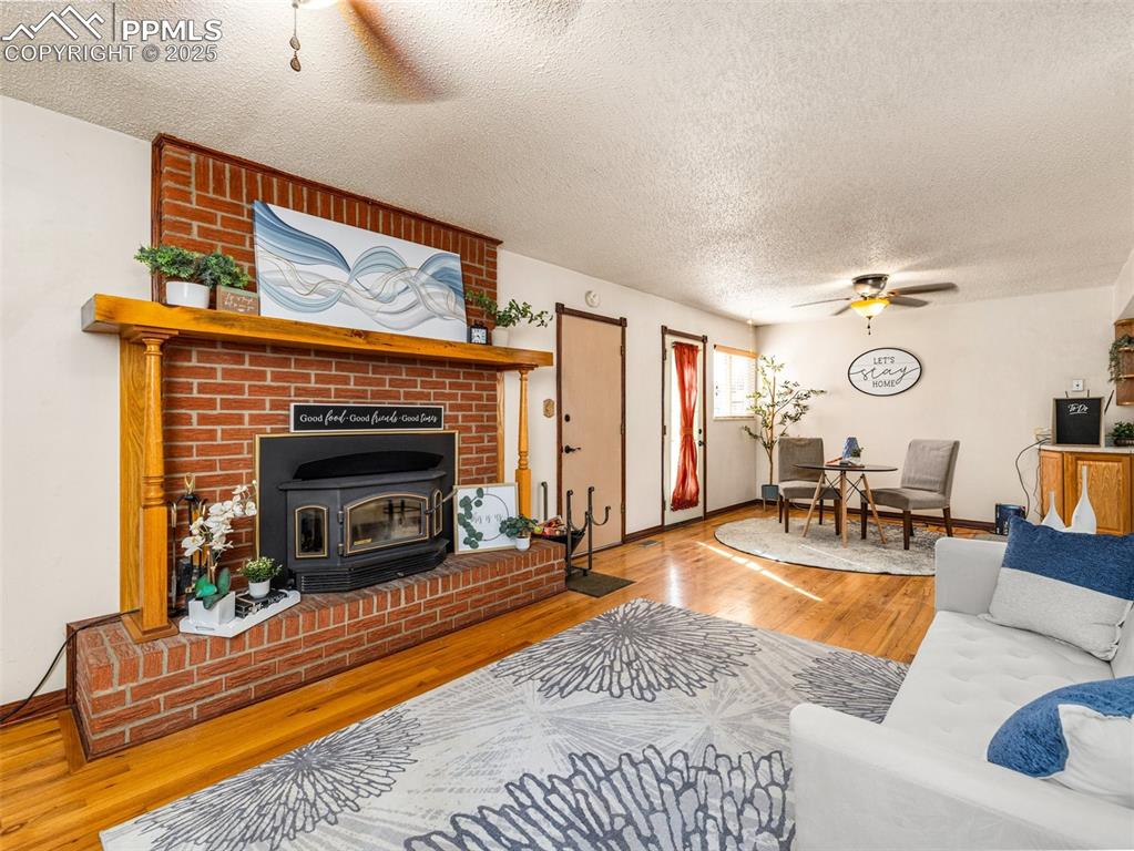Image 10 of 38: Living room with ceiling fan, wood finished floors, a textured ceiling, and