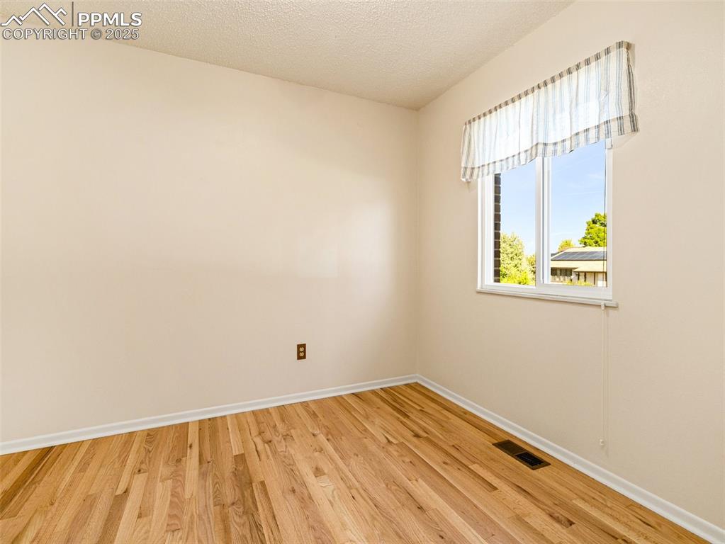 Image 12 of 38: Spare room featuring light wood finished floors and a textured ceiling
