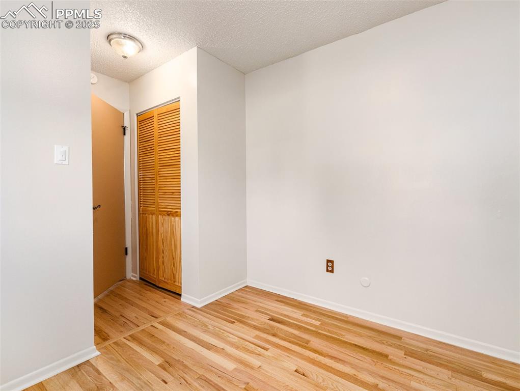 Image 13 of 38: Unfurnished bedroom with a textured ceiling, light wood-style flooring, and