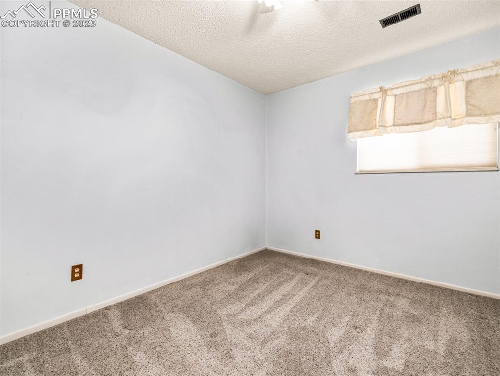 Image 16 of 38: Carpeted empty room with a textured ceiling and baseboards