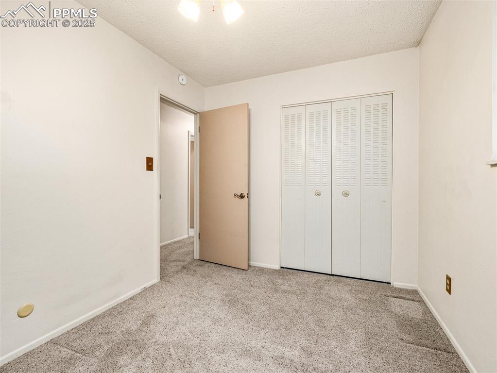 Image 19 of 38: Unfurnished bedroom with carpet, a textured ceiling, and a closet