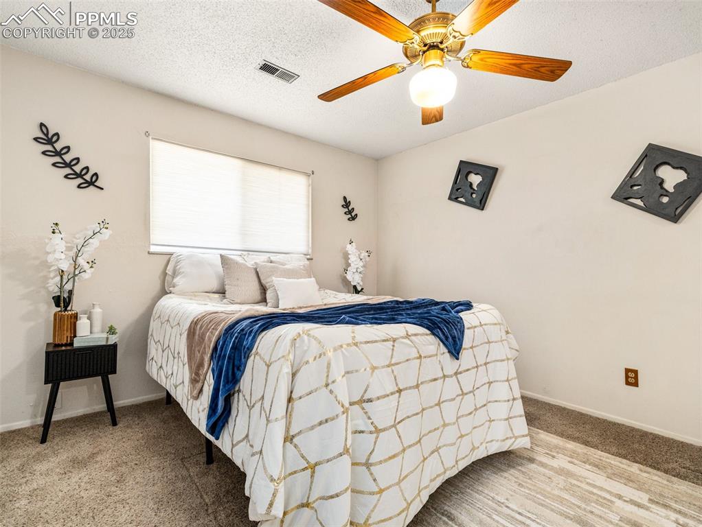 Image 21 of 38: Bedroom featuring a textured ceiling, carpet floors, and a ceiling fan