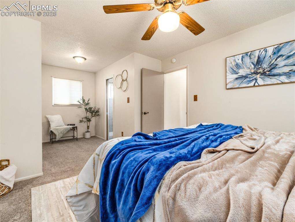 Image 22 of 38: Carpeted bedroom with a textured ceiling and ceiling fan