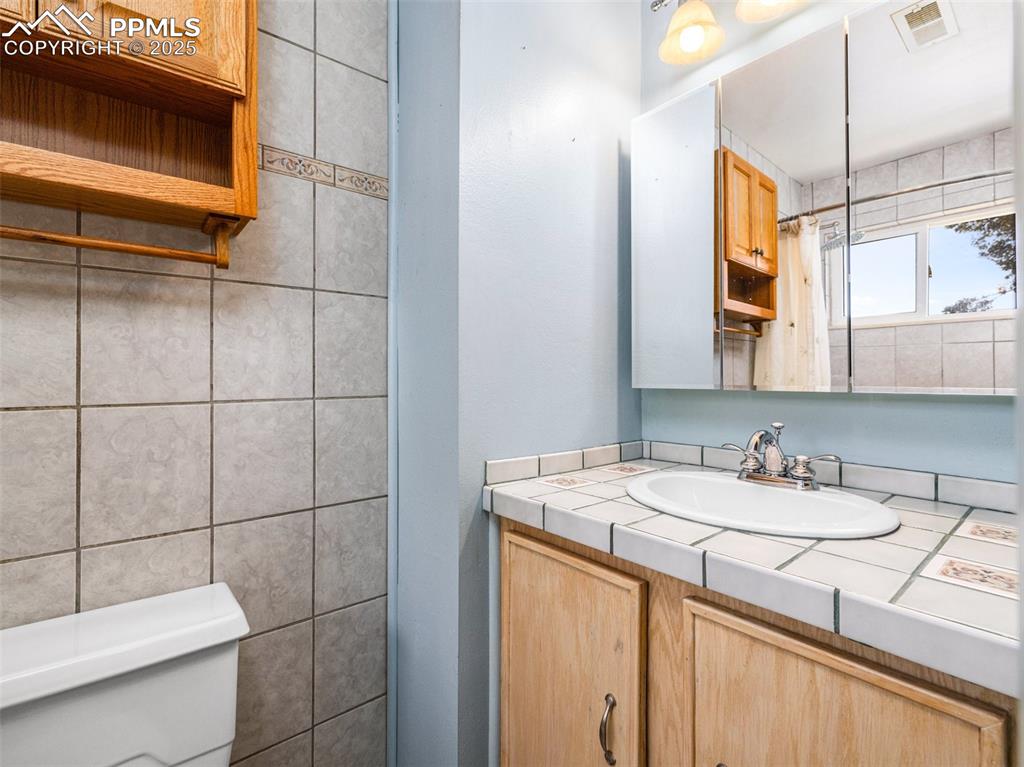 Image 24 of 38: Bathroom featuring vanity, curtained shower, and tile walls