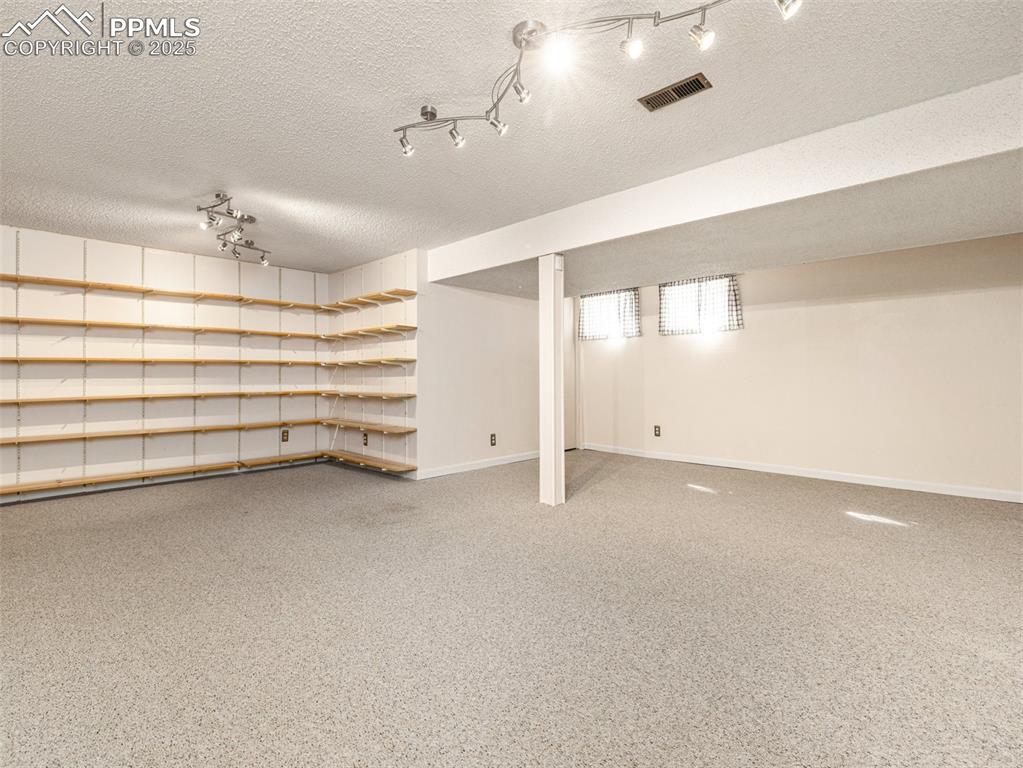 Image 27 of 38: Finished below grade area with a textured ceiling and baseboards