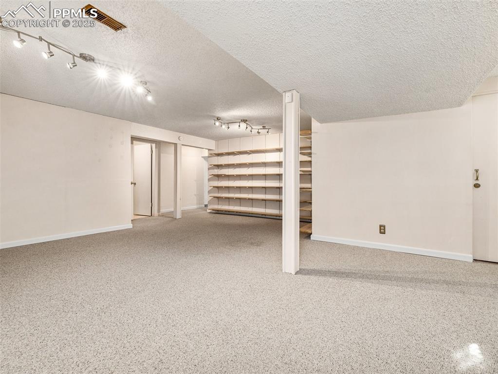 Image 28 of 38: Finished basement with baseboards and a textured ceiling